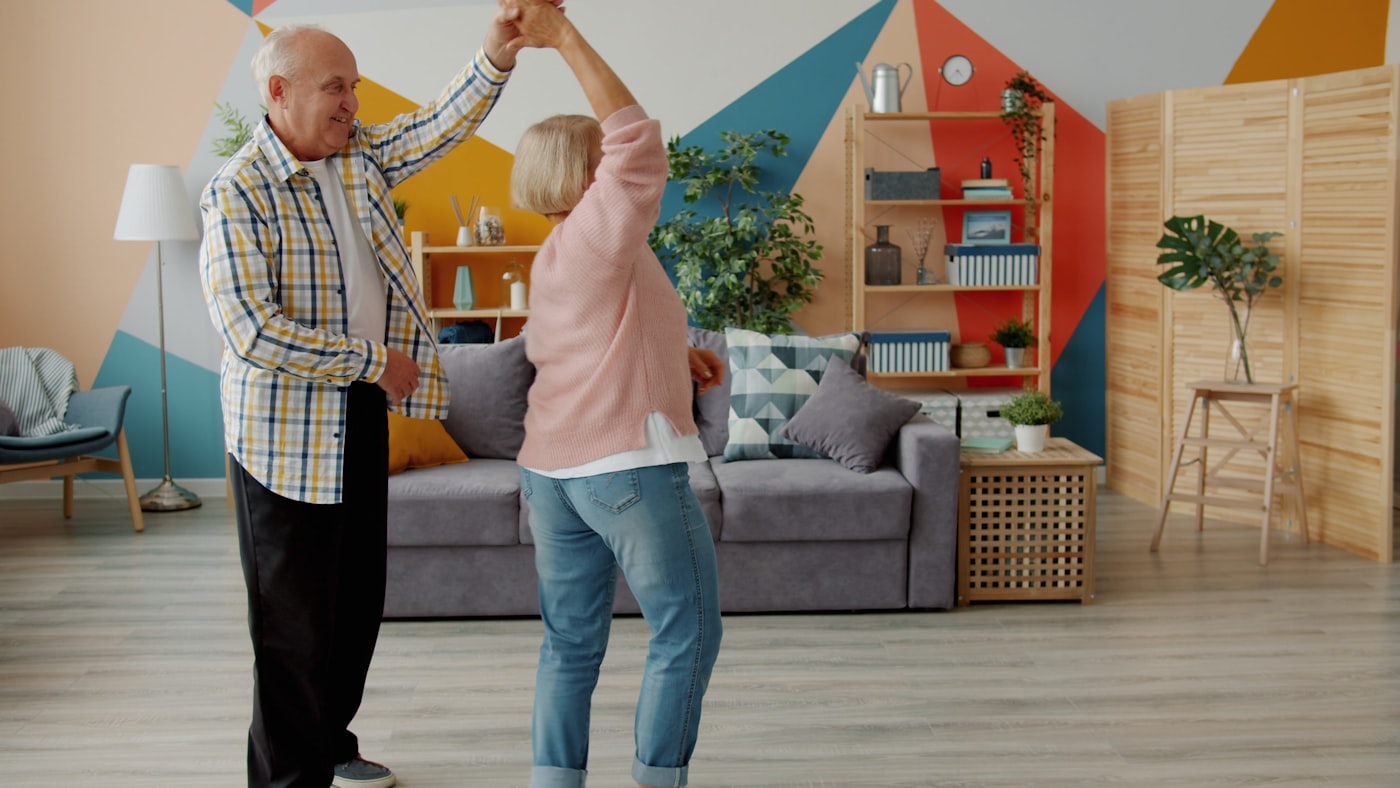 An elderly couple dancing together in their living room