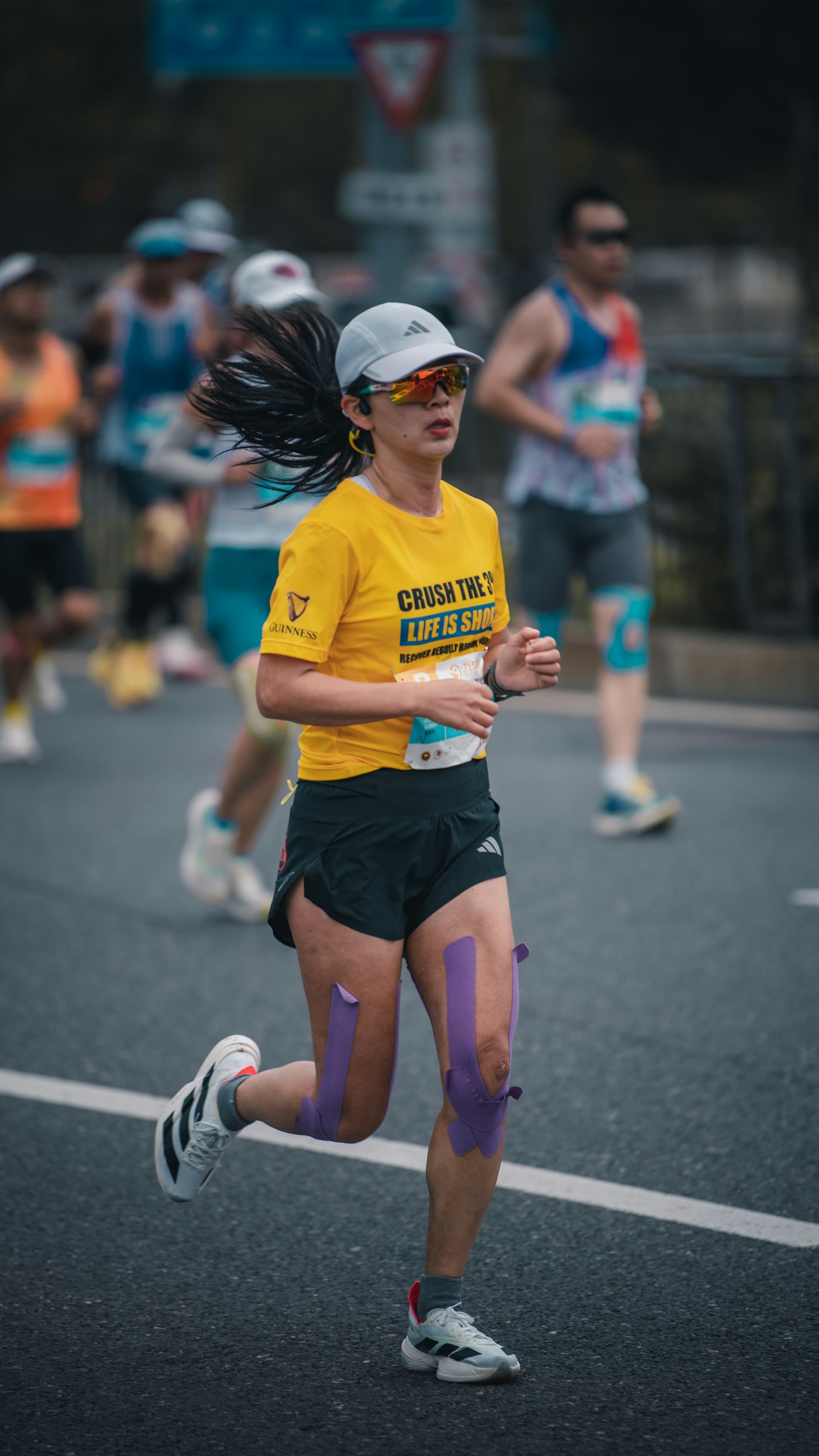 An athlete running with kinesiology tape supporting their legs